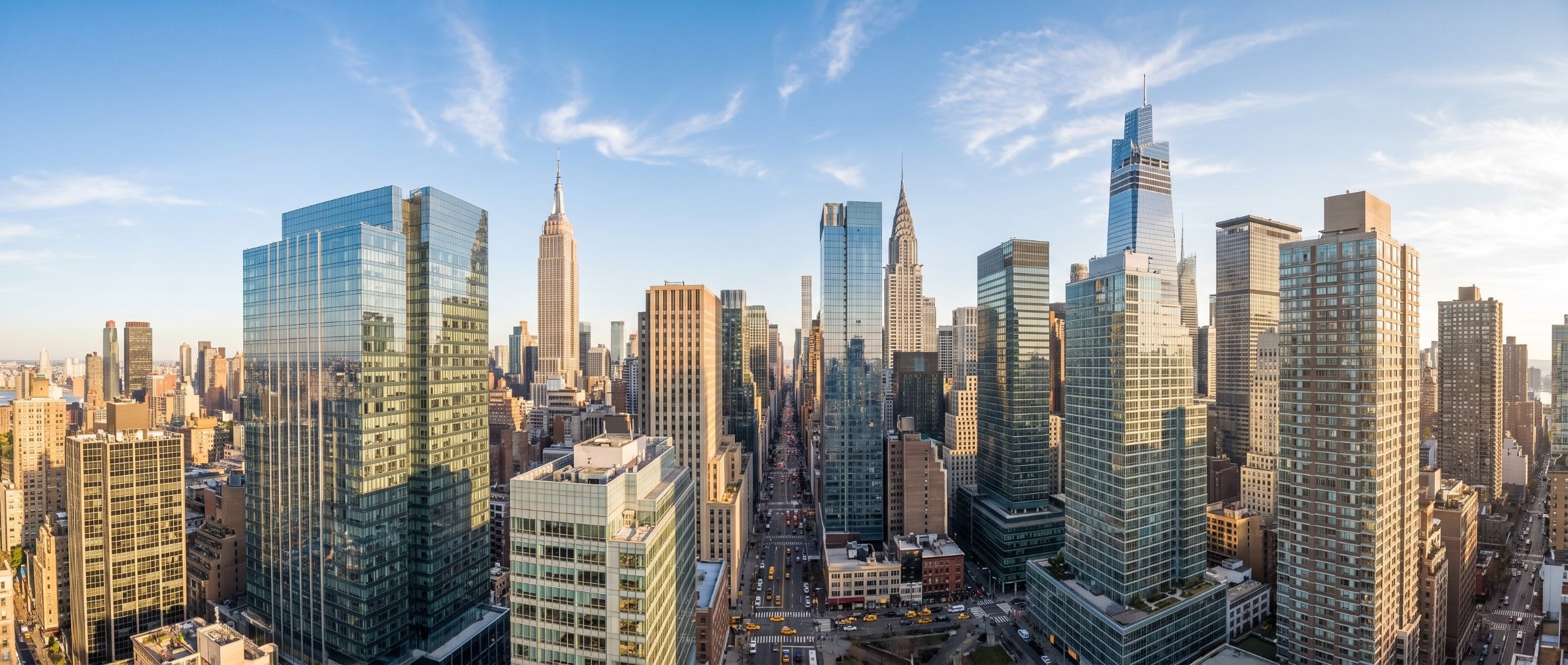 Bright midday aerial view of Midtown Manhattan, clear blue sky, sunlit avenues