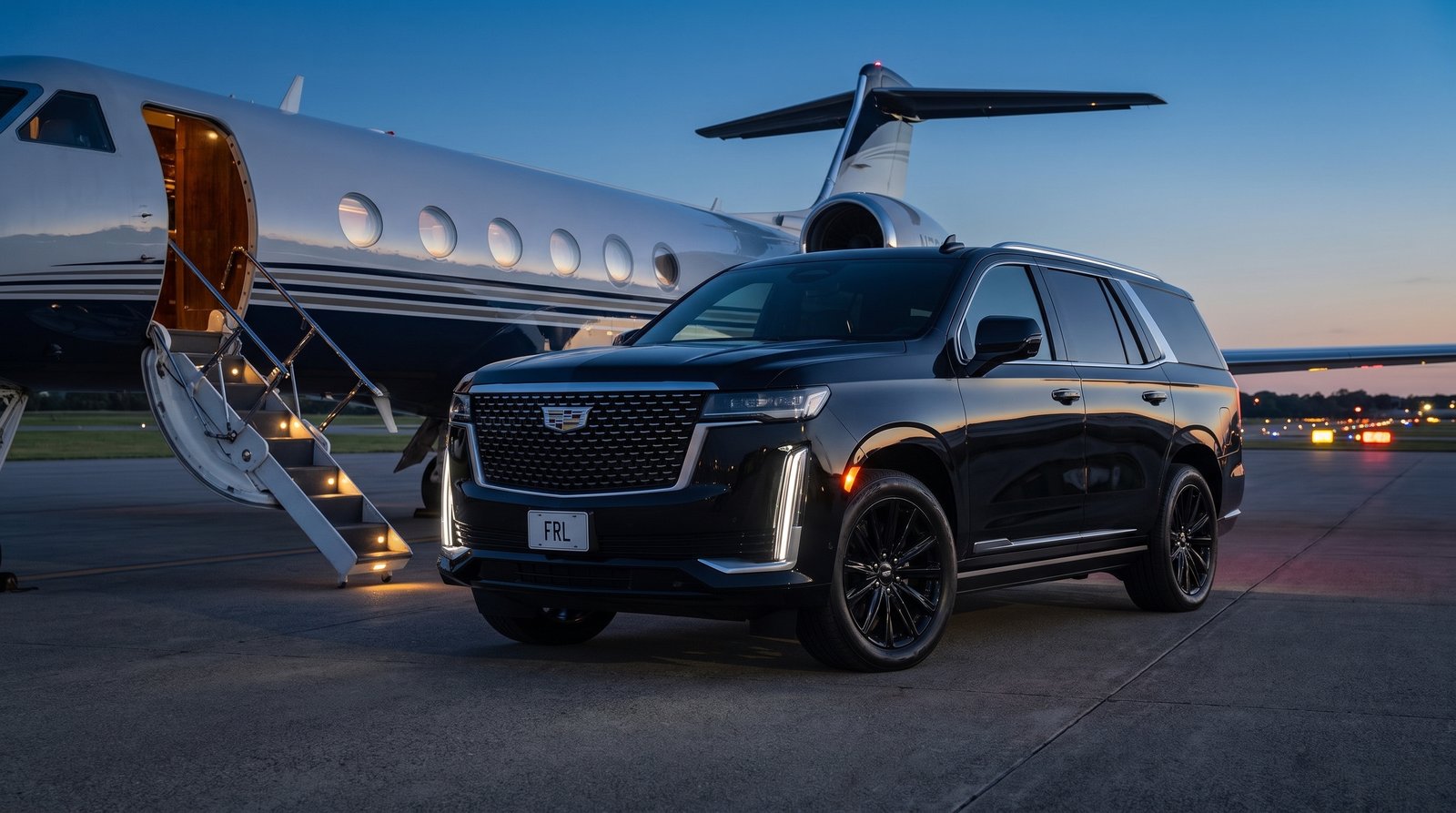 Current-model Cadillac Escalade ESV on a private tarmac beside a jet